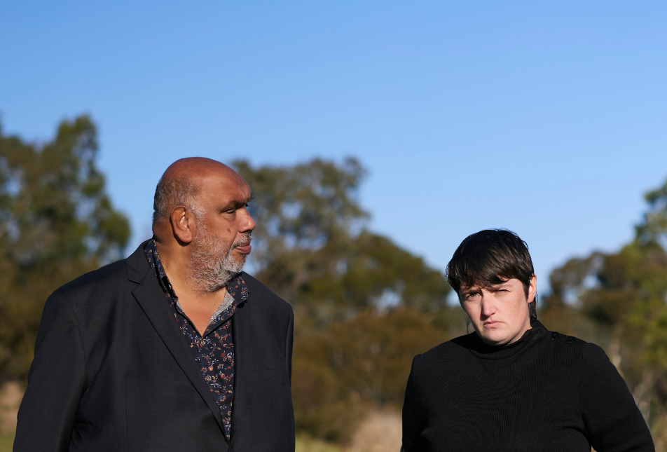 Two men in black shirts stand in bushland