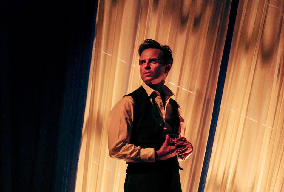 A man stands in the shadows, looking back