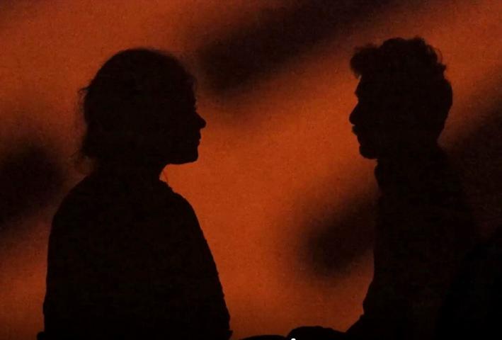 Silhouette of two figures with an orange background