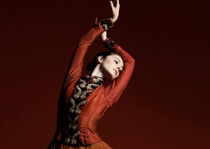 A young ballet dancer with her hands in the air.