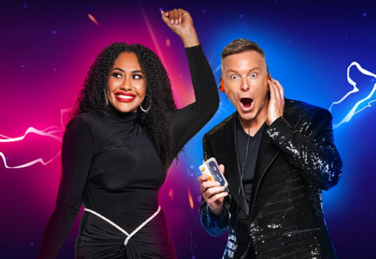 A woman in a black dress dances with her hand up in the air while a man in a suit has a surprised look on his face. 