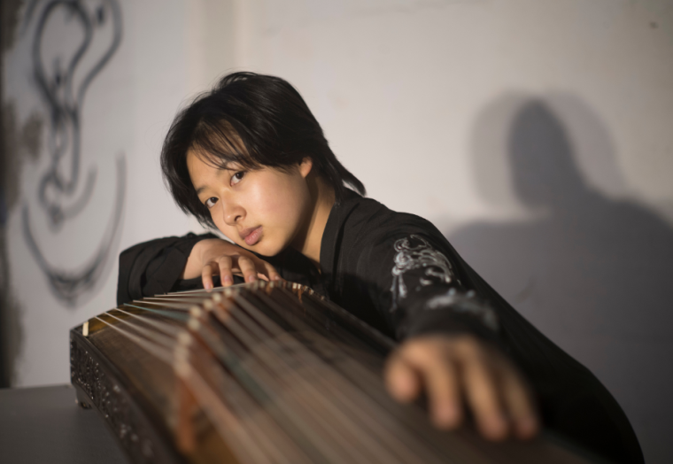 A musician leans across a musical instrument, looking at the camera