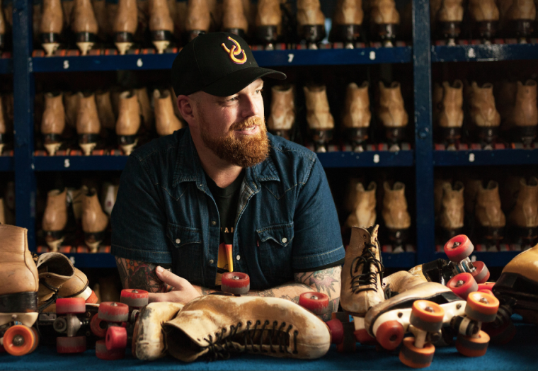 A man in a cap is surrounded by rollerskates.