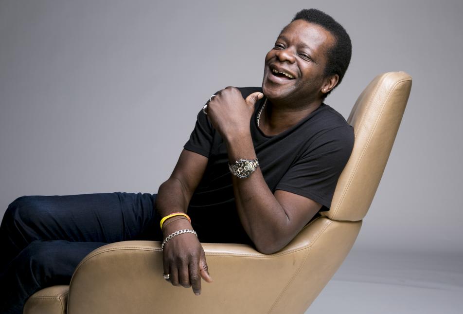 A man leans back in a chair, laughing. 