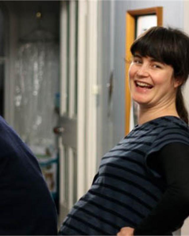 A man and a younger woman look back at the camera, laughing