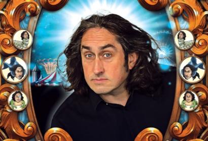 A man with long dark wavy hair looks through a frame that features buttons with his face on creatures - Ross Noble Cranium of Curiosities
